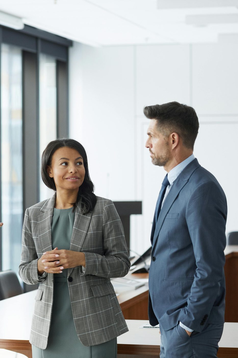 Three business professionals in suits standing in an office, having a conversation